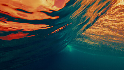 Underwater view of a breaking ocean wave with golden sunset light reflecting through the water surface and dynamic textures. © Dudarev Mikhail