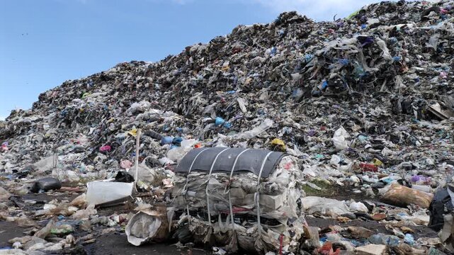 Landfill site displays large piles of municipal waste with various materials stacked high under an open sky, showing waste management challenges