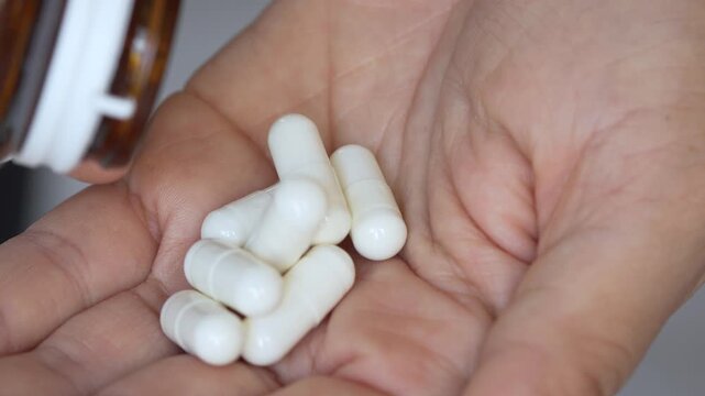 close up hand holding a medicine, with pours the pills out of the medicine bottle. Stop drug use Taking Medication Caring for the health care medical concept. capsule.	
