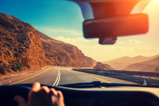 Driving a car on the mountain road in the desert. View of sandstone mountains through the windscreen. The road from Arad to the Dead Sea. Israel