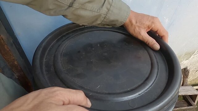 A person recycling kitchen leftovers and food scraps by putting them into a home composting system to reduce waste.