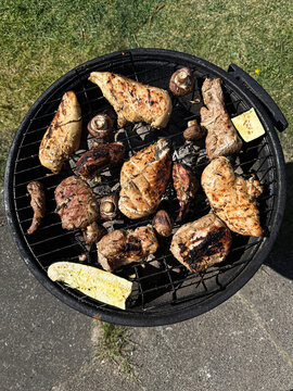 Cooked barbecue meat and mushrooms on a charcoal grill outdoors on a sunny day