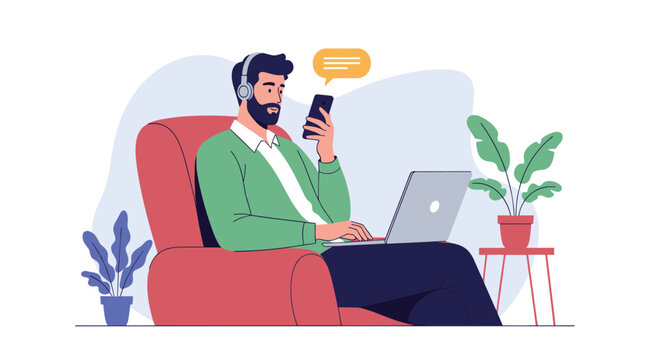 Bearded man relaxes in a red armchair while working on a laptop and checking his smartphone with headphones on in a comfortable home office.