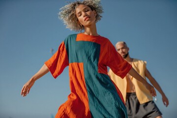 Naklejka premium Young woman dancing with companion on sunlit ocean beach shore