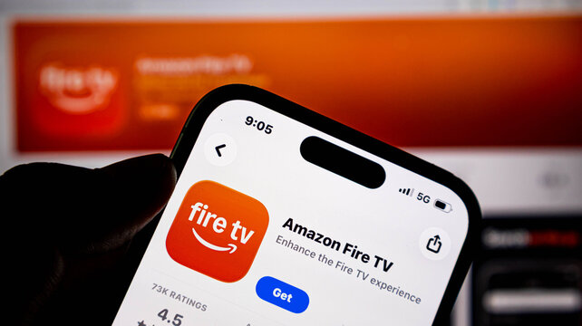 Closeup of a hand holding an iphone displaying the amazon fire tv app page on the apple app store