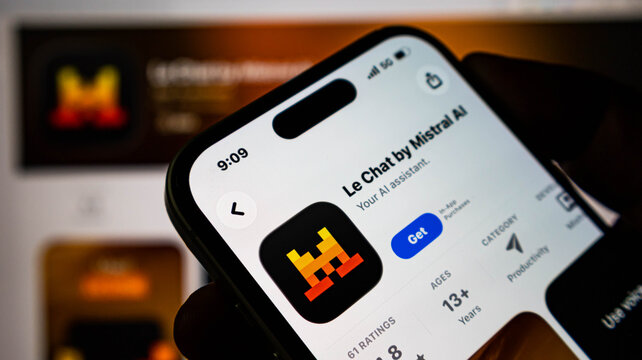 Closeup of a smartphone screen displaying the le chat by mistral ai app page in the apple app store, held by a persons hand