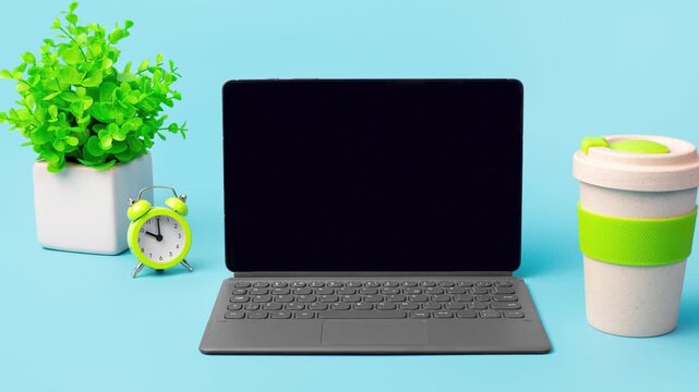 Modern workspace setup with laptop, plant, and coffee cup on blue background