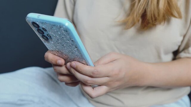 Woman hands holding a smartphone with a decorative case, using the device to type a message, browse the internet, or interact with social media, demonstrating digital communication and connectivity