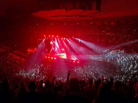 Panoramic high angle view of Italian pop singer Annalisa live arena concert in Rome, large crowd of fans in a packed stadium with dramatic red stage lights