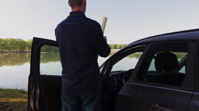 Middle age man get out of the car and searching in paper map. Travel, adventure lifestyle concept