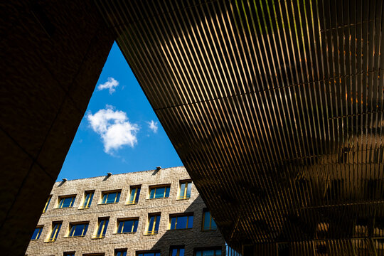 A wood canopy casts shadow beneath open sky in Lyon&rsquo;s La Confluence neighborhood, framing modern urban architecture as a graphic exterior view
