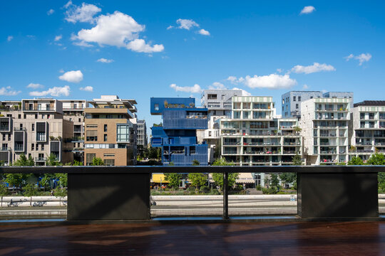 A balcony railing frames apartment buildings across Lyon&rsquo;s La Confluence neighborhood, where sky and urban forms create a clear exterior view