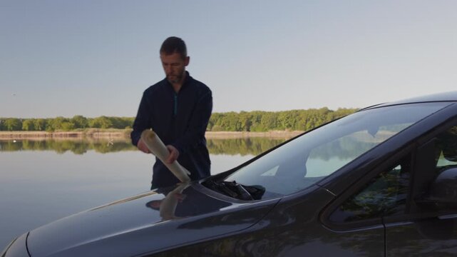 Middle age man searching in paper map on car bonnet. Travel, adventure lifestyle concept