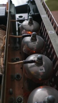 Glowing vacuum tubes operating inside a homemade audio amplifier chassis with internal wiring and a fan visible. This represents a retro electronics and radio engineering concept.