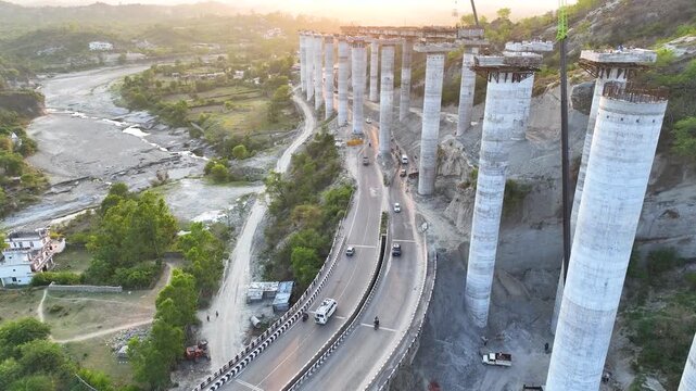 Aerial tracking along giant bridge columns under construction. Detailed aerial drone shot focusing on the active construction phases of colossal concrete bridge pillars. 
