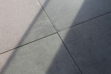 Fototapeta premium Geometric pattern of light and shadow on textured stone tiles