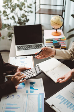 Professional business team analyzing financial data on documents and laptop, working together to calculate budget, reviewing sales statistics in a modern office setup