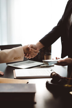 Two people shake hands while one slips a hidden stack of cash under a document, symbolizing bribery, corruption, illegal deals and unethical corporate transactions