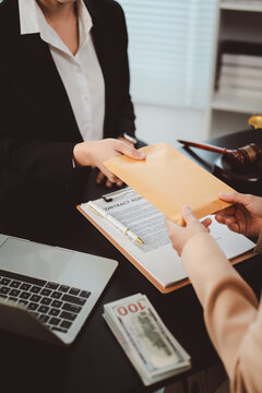 Businesswoman giving envelope with money to another person as a bribe in an illegal deal, highlighting concepts of corruption, illegal payments, and financial crime
