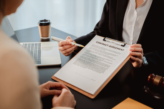 Lawyer or financial advisor explaining contract agreement details to a client, pointing out important clauses for signing during a business meeting