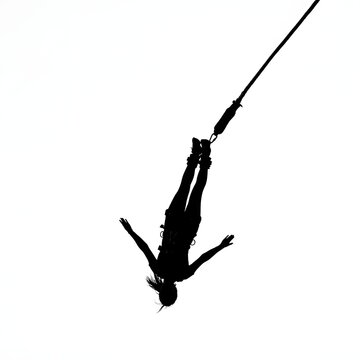 Silhouette of person bungee jumping against bright white background