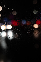 Fototapeta premium Rain on Window at Night with Blurred City Lights. Moody Urban Background. Raindrops