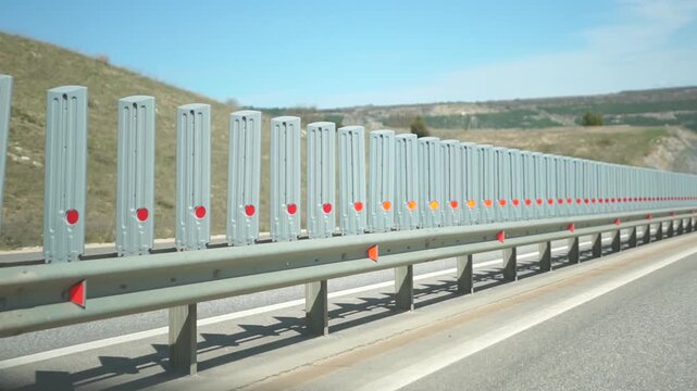 Highway Safety Barriers Roadside Protection - A row of highway safety barriers with reflective strips on a roadside in a sunny day.