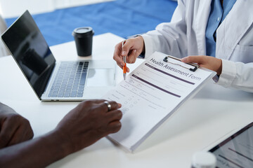 Fototapeta premium Doctor presenting a health assessment form to a patient during a medical consultation at a clinic, discussing healthcare information and personal details for an annual check-up
