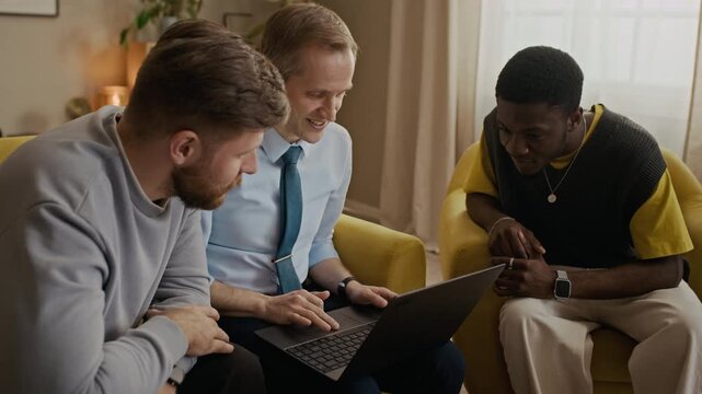 Handheld shot of three best friends sitting on sofa in living room, looking at laptop screen, watching funny videos on social network and laughing