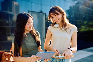 Fototapeta premium Two happy students smiling and learning together outdoors on university campus