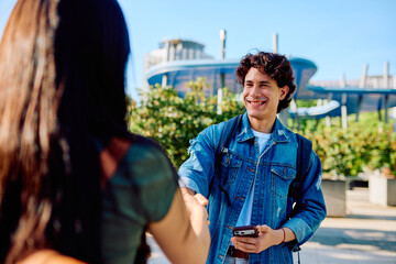Happy student smiling while shaking hand with a person on campus © we.bond.creations