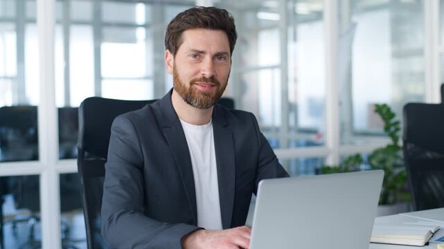 Caucasian middle-aged 40s business man working with laptop technology smiling happy posing at table looking at camera European mature businessman male entrepreneur work with computer smile in office