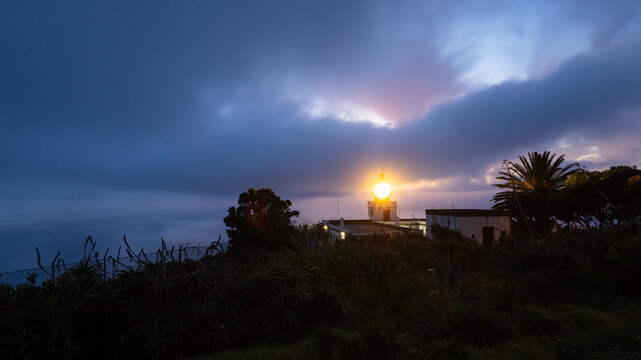 Lighthouse beam shining at twilight on cloudy evening in Madeira Island