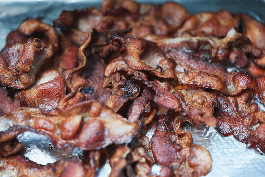 Crispy bacon covered in grease and hot oil for breakfast. The delicious pork belly is tasty food and ready for a meal. 