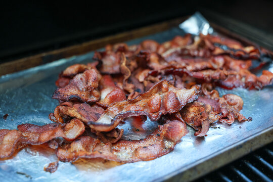 Crispy bacon covered in grease and hot oil for breakfast. The delicious pork belly is tasty food and ready for a meal. 