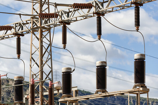 Close-up of ceramic insulators and electrical switching equipment inside industrial power substation. Infrastructure components used for electrical isolation and voltage control in transmission system