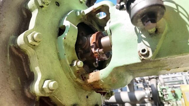 Slow motion close-up footage of an industrial rotating shaft and coupling assembly during maintenance inspection.