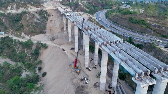 High angle view of curved unfinished highway bridge construction showing heavy civil engineering and infrastructure growth.