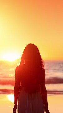 Attractive Asian woman enjoys a walk on the beach at sunset in Southern California. Slow Motion. Vertical Video.