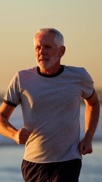 64 year old man getting his exercise at the beach at sunset. Slow Motion. Vertical Video.