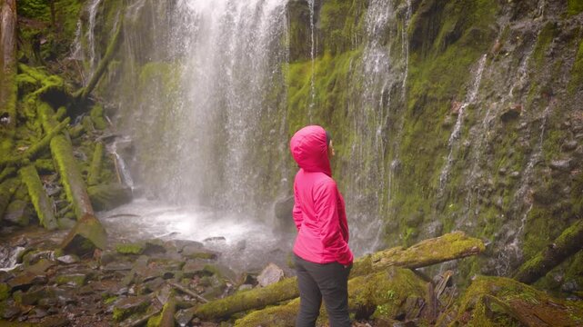 Woman hiker enjoying the view of the lush forest and moss at Proxy Falls in Oregon, USA.