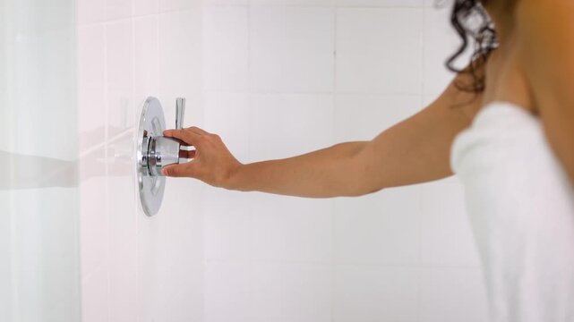 Close-up of a woman's hand turning on the shower before entering.