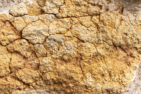 Full frame texture of cracked old rustic yellow ochre limestone wall
