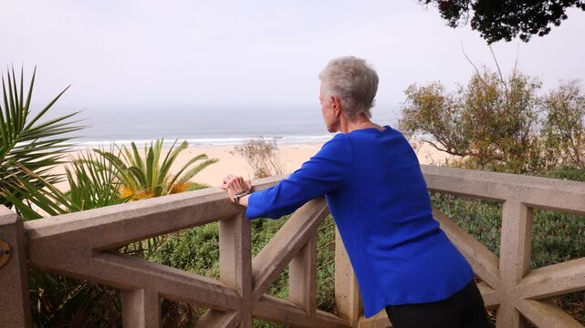 Senior woman gets her morning exercise at a park overlooking the Santa Monica beach. Checks her fitness on a smark watch.