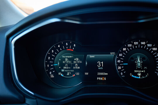 Illuminated car dashboard with tachometer, digital speed display and trip computer screen. Concept of driving, vehicle control, onboard information and automotive technology.