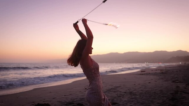 Attractive woman fire dancer spinning flames at the beach. Slow Motion.