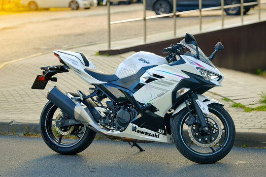 Minsk, Belarus. Aug 23, 2025. White Kawasaki Ninja sport motorcycle. Sportbike in white and blue colors, detailed disc brakes and stylish fairings standing on kickstand in an outdoor parking area