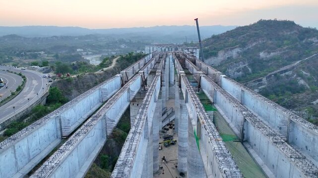 High angle view of curved unfinished highway bridge construction showing giant concrete pillars for new flyover