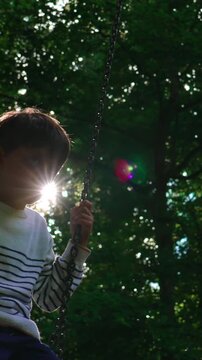 Pensive child resting alone on backyard swing beneath shaded woodland trees during quiet summer afternoon conveying emotional stillness solitude