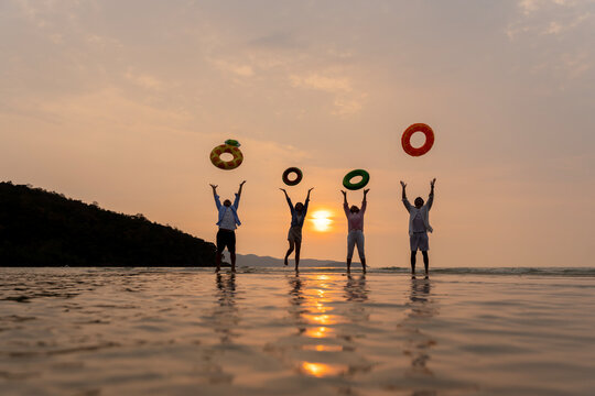 Golden Happiness: Joyful Multi-generational Family Jumping on the Beach at Sunset